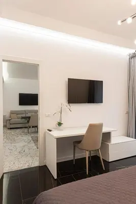a white desk with a chair and a television on a wall at Casa Malupa Luxury Apartments in Rome