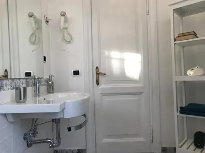 a white bathroom with a sink and a door at The Flower Market Apartment in Rome