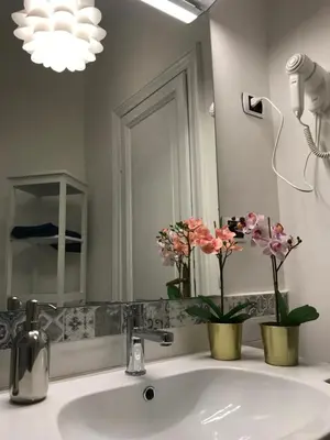 a bathroom with a sink and a mirror and flowers at The Flower Market Apartment in Rome