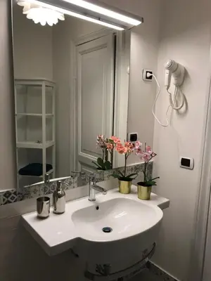 a bathroom with a sink and a mirror and flowers at The Flower Market Apartment in Rome