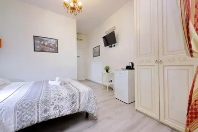 a white bedroom with a bed and a tv at Lucky Holiday Rooms in Rome