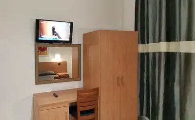 a room with a desk and a mirror and a television at Friendship Place in Rome