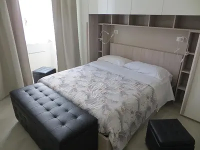 a bedroom with a bed with a leather tufted footboard and a bench at San Pietro house in Rome