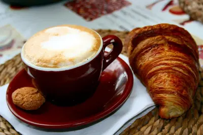 a cup of coffee and a croissant on a table at Chic 'N Charme Trastevere Terrace in Rome