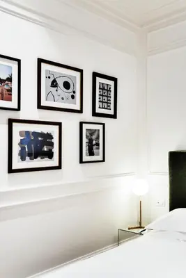 a white bedroom with framed pictures on a wall at The Shire Hotel in Rome