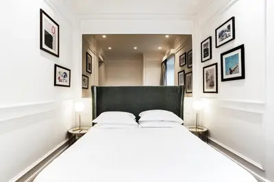 a white bedroom with a large bed with two lamps at The Shire Hotel in Rome