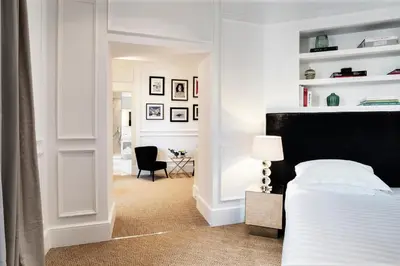 a white bedroom with a bed and a chair at The Shire Hotel in Rome