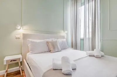 a white bedroom with a bed with white sheets and pillows at Vatican City Guest House in Rome
