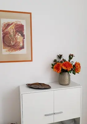 a white cabinet with a vase of flowers and a picture at Il sole del Vaticano in Rome
