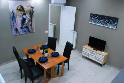 a dining room with a table with chairs and a television at RHOMENJOY Suite Vatican in Rome
