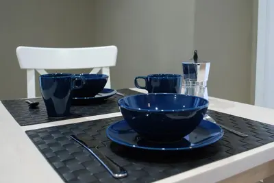 a table with three blue bowls and a white chair at RHOMENJOY Suite Vatican in Rome