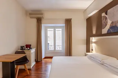 a bedroom with a bed and a table and a window at Inn Rome Rooms & Suites in Rome