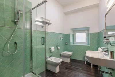 a bathroom with two toilets and a sink and a shower at Inn Rome Rooms & Suites in Rome