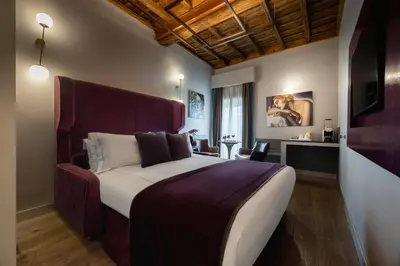 a hotel room with a bed and a flat screen tv at Maison Torre Argentina in Rome