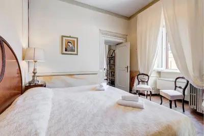 a white bedroom with a large bed and two chairs at Palazzo Giorgioli Apartment in Rome