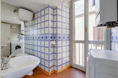 a bathroom with a white sink and a blue tiled wall at Palazzo Giorgioli Apartment in Rome