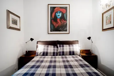a bedroom with a checkered bed with a painting on the wall at Santa Cecilia Apartment in Via del Corso in Rome