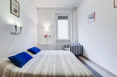 a white bedroom with a bed and a chair at Appartamento con 3 camere da letto e 2 bagni vicino al Vaticano in Rome