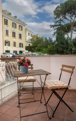 a table and two chairs on a balcony with flowers at Comfy Vatican Suite in Rome