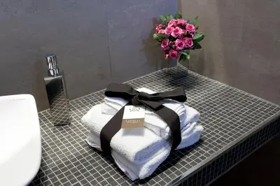 a bunch of towels on a bathroom counter with a vase of flowers at Cardilli Luxury Rooms in Rome