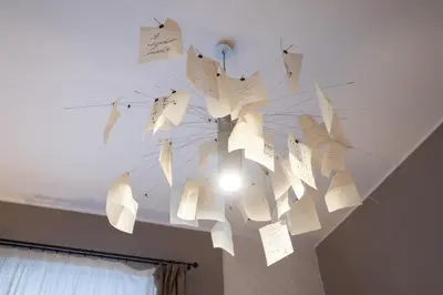 a chandelier with paper notes hanging from a ceiling at Cardilli Luxury Rooms in Rome