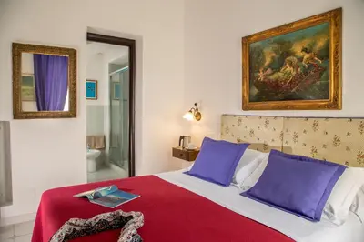 a bedroom with a bed with purple pillows and a painting at Roma Central Guest House in Rome
