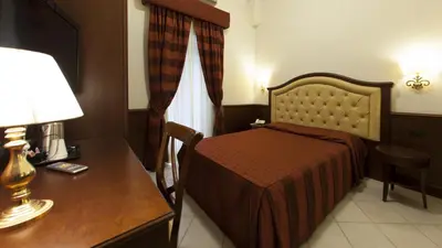 a hotel room with a bed and a desk with a lamp at Domus Augusta in Rome