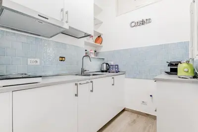 a white kitchen with white cabinets and blue tiles at Giulia's holidays in Rome