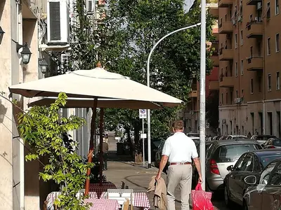 a man walking down a street with an umbrella at Roma Metro Furio Camillo in Rome