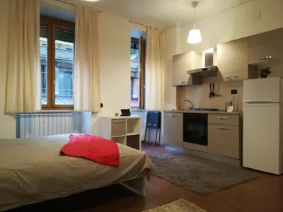 a bedroom with a bed and a kitchen with a refrigerator at Roma Metro Furio Camillo in Rome