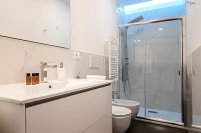 a white bathroom with a shower and a toilet at Quiriti Vatican Relais in Rome