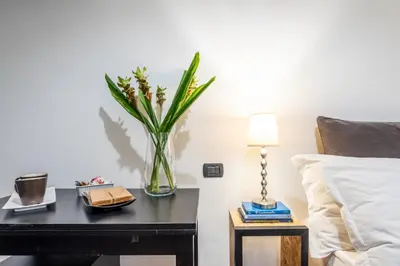 a vase of flowers on a table next to a bed at Suite 36 in Rome