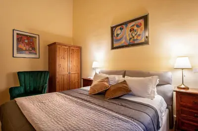 a bedroom with a bed and a green chair at Residenza Sinibaldi - XVII century experience in Rome