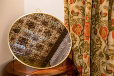 a mirror sitting on a table next to a curtain at Residenza Sinibaldi - XVII century experience in Rome