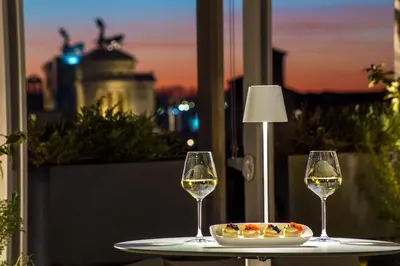 two glasses of wine and a plate of food on a table at Monti Palace Hotel in Rome