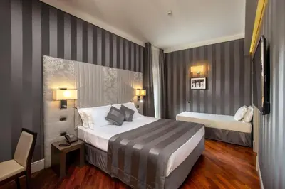 a hotel room with two beds and a chair at Monti Palace Hotel in Rome