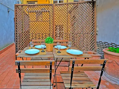 a wooden table with two chairs and a table with wine glasses at Terrace Governo Vecchio in Rome
