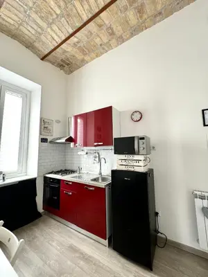 a kitchen with red cabinets and a black refrigerator at CasualSuiteMachiavelli in Rome