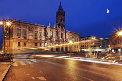 a city street at night with a building with a clock tower at Hotel Chicago in Rome