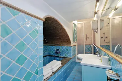 a blue tiled bathroom with a sink and a mirror at Characteristic apartment just beside the Vatican in Rome