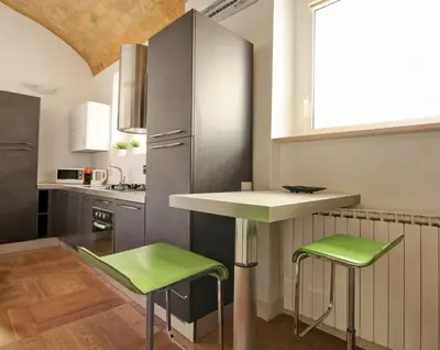 a kitchen with a counter and two green stools at Maisonette Coppedé in Rome