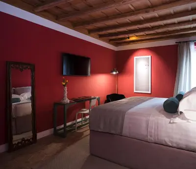 a bedroom with red walls and a bed and a mirror at Palazzo Caruso in Rome
