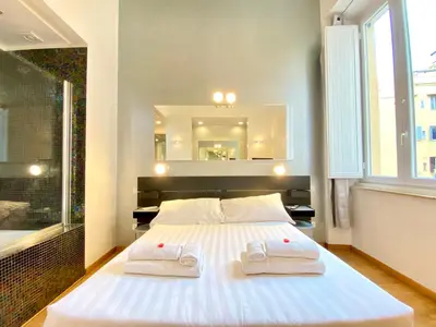 a bedroom with a large white bed with towels on it at KISS ME ROME Luxury Rooms in Rome