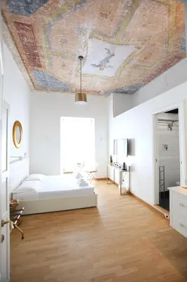 a bedroom with a ceiling with a painting on it at KISS ME ROME Luxury Rooms in Rome