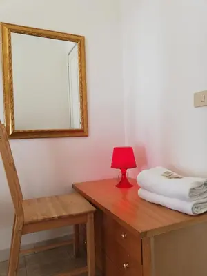 a red lamp sitting on a wooden table with a chair at Varese Guest House in Rome