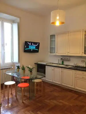 a kitchen with a table and a tv on the wall at Varese Guest House in Rome