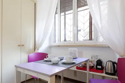 a table with two purple chairs and a window at Maison Colosseo (Via dei Querceti 24) in Rome