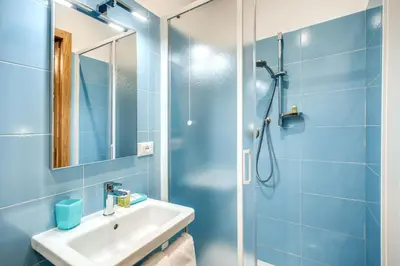 a blue bathroom with a shower and a sink at La Residenza Suites in Rome