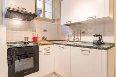 a kitchen with white cabinets and a black stove top oven at GuestHost - Campo De' Fiori Central Flat in Rome