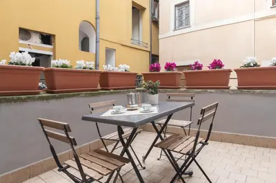 a table and chairs on a balcony with flowers at GuestHost - Campo De' Fiori Central Flat in Rome